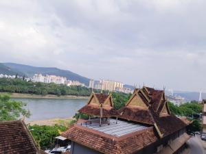 a building with a roof next to a river at Xishuangbanna Aerial Garden Daijiangnan Mekong River South Business Hotel in Jinghong