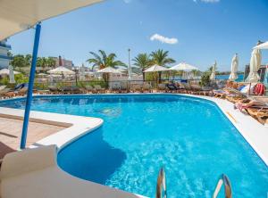 una piscina con sillas y sombrillas en un hotel en Hotel Osiris Ibiza en San Antonio