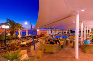 サンアントニオにあるHotel Osiris Ibizaの大傘下に座る人々のいるレストラン
