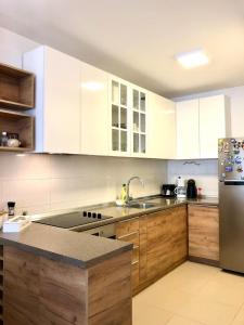 a kitchen with white cabinets and a stainless steel refrigerator at Modern Cosy Apartment by SMM in Skopje