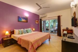 a bedroom with a bed with a purple wall at Heritage Exotica Villa - 4BHK, Baga in Baga