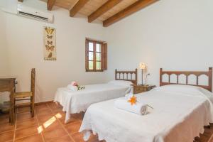 two beds in a room with white walls and wooden floors at Mercader in Alcudia +35 photos