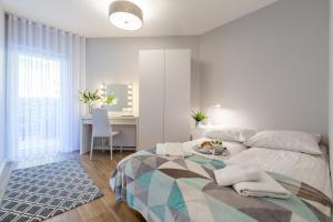 a white bedroom with a bed and a desk at Biały Apartament in Szczyrk