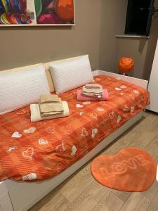 ein Bett mit einer orangefarbenen Bettdecke und einem Herzteppich in der Unterkunft Casa Rosina in Palermo