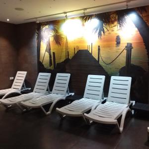 four white lounge chairs in a room with a painting at Orbi Palace - Orbi Deluxe in Bakuriani