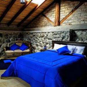 Un dormitorio con una cama azul y una pared de piedra en La Montaña Restaurante Mirador, en Patate