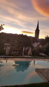 a view of a church and a pool with a church at Hotel Goldener Stern in Caldaro