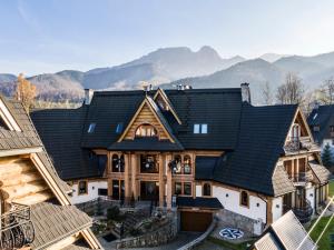a house with a black roof with mountains in the background at Apartament Zacisze pod Giewontem in Zakopane