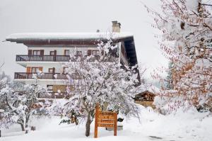 une cour enneigée avec un bâtiment en arrière-plan dans l'établissement Coeur des Alpes, à Combloux