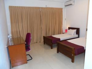 ネゴンボにあるJMF Hotelのベッド2台、デスク、椅子が備わるホテルルームです。