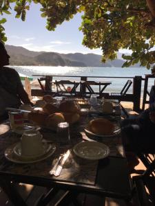 a table with food on it with a view of the ocean at Jambeiro na praia in Trindade