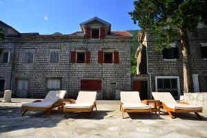 a group of chairs sitting in front of a brick building at A Hundred Olive Trees Apartments in Kotor