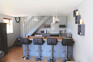 a kitchen with a counter with stools and a staircase at Dolmen Cottage in Glencolumbkille