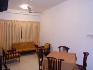 een woonkamer met een bank en een tafel en stoelen bij JMF Hotel in Negombo