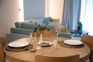 a wooden table with plates and wine glasses on it at Onar Modern Luxury Apartments in Kavala