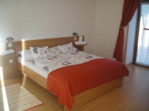 a bedroom with a bed with a red blanket at Paks Panzió in Paks