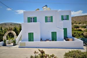 een wit huis met groene deuren op een heuvel bij Dioni lux inn in Pachaina