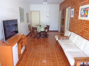 ein Wohnzimmer mit einem Sofa, einem TV und einem Tisch in der Unterkunft Apartamento praia do forte in Cabo Frio