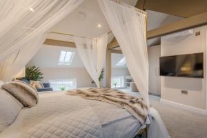 a bedroom with a bed with white curtains and a tv at Heritage Mews Nottingham in Nottingham