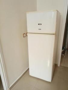 einen weißen Kühlschrank in einem Zimmer mit einer weißen Wand in der Unterkunft Sheffer in Ramat Gan