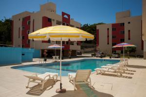 a pool with chairs and an umbrella next to a building at HOSTEL SERUSSI in Balneário Camboriú