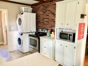 a kitchen with a microwave and a washer and dryer at KING BED Family Friendly Cottage - Walk to Zoo & Waterpark - Near Downtown & Midtown in Hattiesburg +31 photos