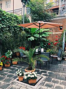 a patio with a table with an umbrella and plants at Apartment Botanikuri 15 in Tbilisi City
