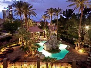 a resort pool with a fountain and palm trees at night at Lovely condo! Walking distance to the Strip with pool and spa in Las Vegas
