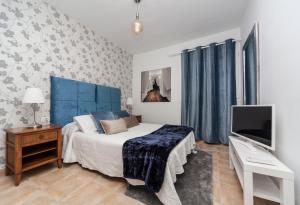 a bedroom with a bed with a blue headboard and a television at Luxury Suite Sea Front in Playa Honda