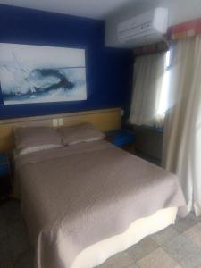 - une chambre avec un lit et un mur bleu dans l'établissement Costeira Praia, à Natal
