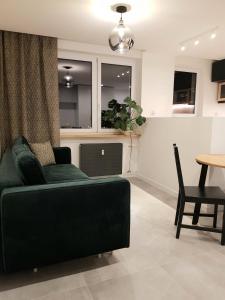 a living room with a green couch and a table at MISVEST Maria IV Arena Gliwice in Gliwice