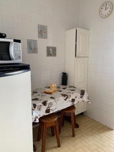 a kitchen with a table with chairs and a microwave at Pé na Areia in Arraial do Cabo