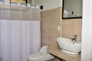 La salle de bains est pourvue d'un rideau de douche blanc et d'un lavabo. dans l'établissement Cabañas Green House, à San Vito