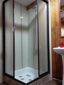 y baño con ducha de cristal y lavabo. en Hostal Don Pedro, en Puerto Natales