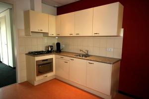 uma cozinha com armários brancos e um lavatório em Vakantie-Oord "De Hulsdonken" em Bergeijk