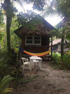 a hammock and two chairs in front of a house at Cabaña Rio Lagarto in Lívingston