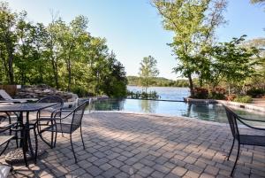 a patio with a table and chairs next to a body of water at Chalets Resort Luxury Lakefront Villa Family Friendly 2 Pools Free Amenities in Lampe