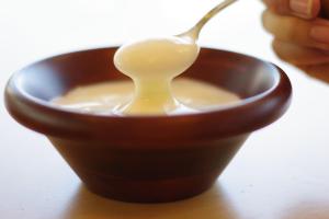 a person holding a spoon in a bowl of milk at Kyukamura Iwate-Amiharionsen in Shizukuishi