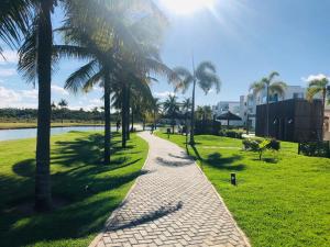 a walkway with palm trees next to a body of water at O Paraíso que você merece in Praia do Forte