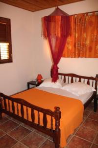 una camera con letto in legno e coperta arancione di RESIDENCE LA TAUPINE MANDARINE a Le Diamant
