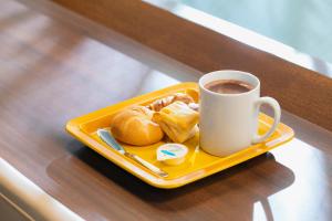 una bandeja de bollería y una taza de café sobre una mesa en Hotel Wing International Shimbashi Onarimon, en Tokio