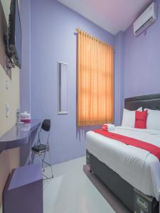 1 dormitorio con cama, escritorio y ventana en RedDoorz @ Gatot Subroto Street Bandung 3, en Bandung