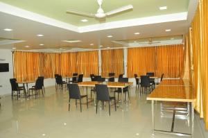 a conference room with tables and chairs and orange curtains at Hotel Shiva's Inn in Trimbak +36 photos
