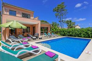 a house with a swimming pool with chairs and an umbrella at Villa Marioma in Cala de Sant Vicent