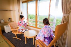 two women sitting in chairs looking out of a window at Kyukamura Iwate-Amiharionsen in Shizukuishi