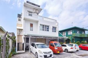 a white building with cars parked in a parking lot at Wind Makiminato in Makiminato
