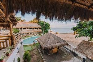 a resort with a swimming pool and a straw roof at Lavanya Beach And Dive Resort in Zamboanguita