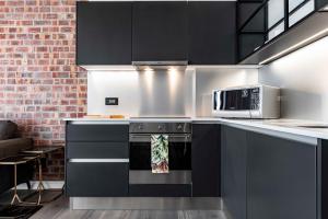 eine Küche mit schwarzen Schränken und einer Mikrowelle in der Unterkunft 402 The Signature, De Waterkant in Kapstadt + 4 Fotos