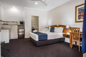 a bedroom with a bed and a desk and a kitchen at Karratha Central Apartments in Karratha