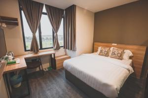 um quarto de hotel com uma cama, uma secretária e janelas em V3 Hotel & Residence Seri Alam em Pasir Gudang